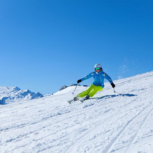 Skifahrer auf der Schmittenhöhe mit Kitzsteinhorn im Hintergrund